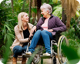 Support worker sitting with a participant in a wheelchair in a garden